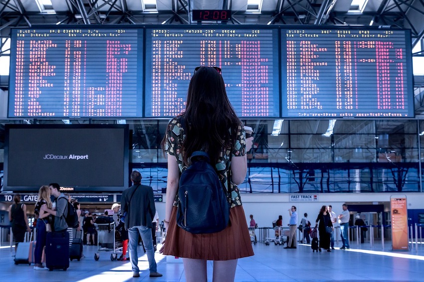 Passenger Looking at the Flight Information Board at the Airport